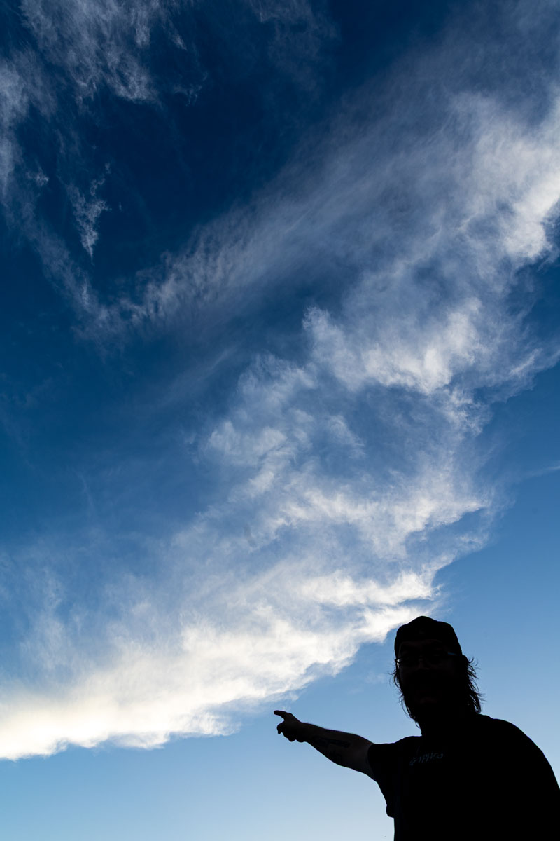 A silhouetted man pointing at the clouds.